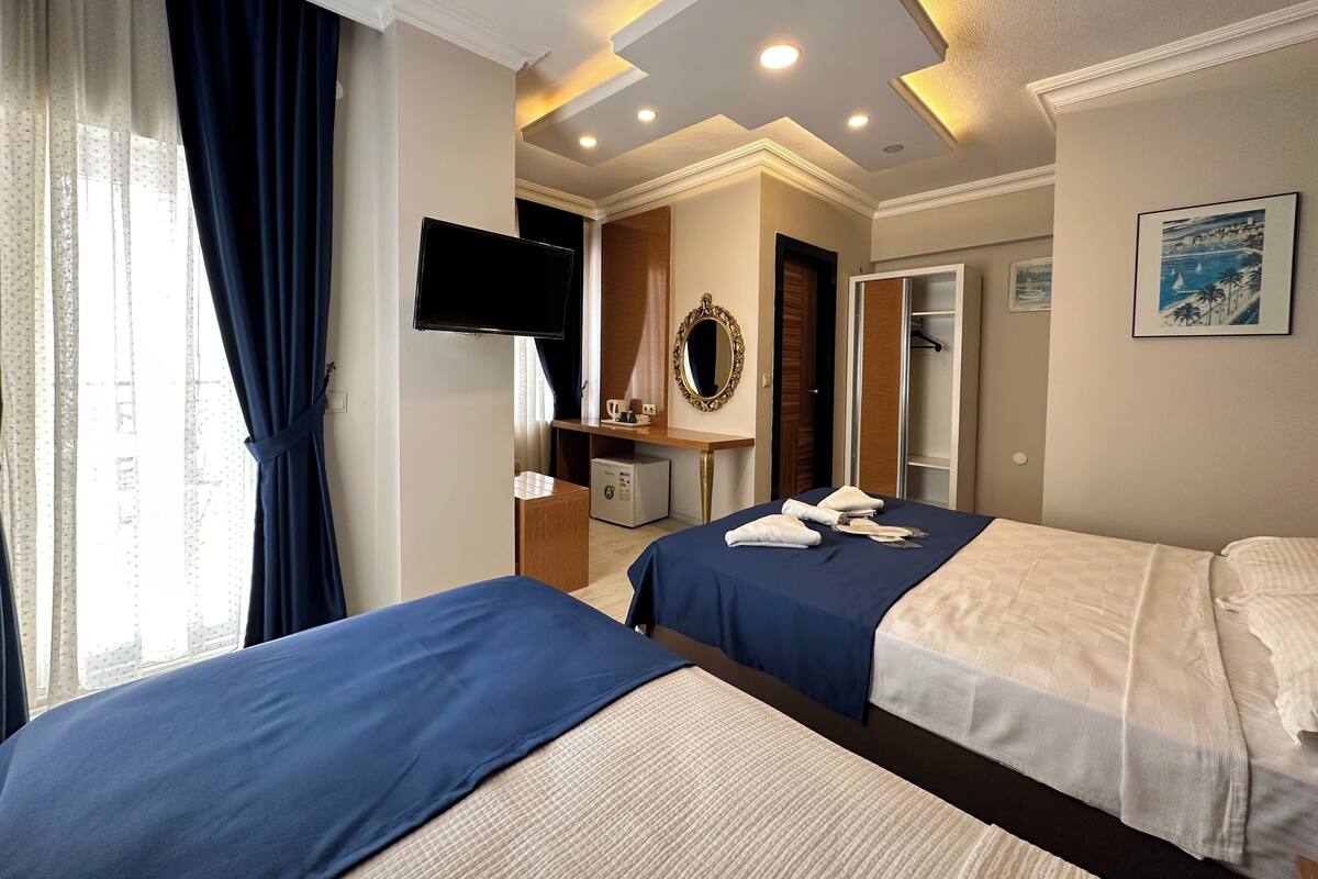 Une chambre d’hôtel avec deux lits, une télévision, un bureau, un miroir et une armoire.