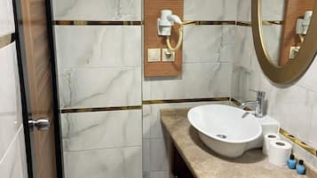 A bathroom with a marble floor, a wooden vanity, a sink, a mirror, and a towel rack.