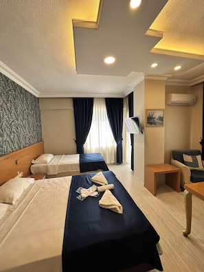 A hotel room with two beds, a desk, a chair, a TV, and an air conditioning unit. - serenity suıtes otel konyaaltı (Konyaalti)
