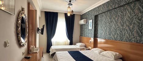 A hotel room with two beds, a desk, a mirror, and a ceiling fan.
