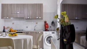 A modern kitchen with a dining area, a washing machine, and a vase with flowers on the counter.