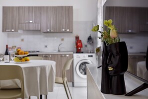 A modern kitchen with a dining area, a washing machine, and a vase with flowers on the counter. - Casa Sole e Mare with Mountain View, Wi-Fi and Air Conditioning (Palermo)