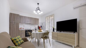 A modern living room with a sofa, a dining table, and a TV.