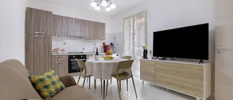 A modern living room with a sofa, a dining table, and a TV.