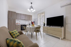 A modern living room with a sofa, a dining table, and a TV. - Casa Sole e Mare with Mountain View, Wi-Fi and Air Conditioning (Palermo)