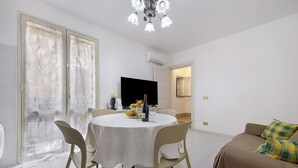 A dining area with a round table, chairs, and a TV.