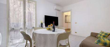 Un comedor con una mesa redonda, sillas y un televisor.