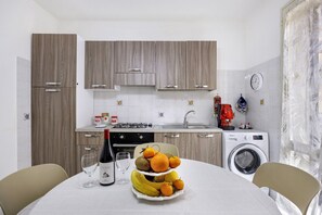 A modern kitchen with wooden cabinets, a sink, a stove, and a washing machine. - Casa Sole e Mare with Mountain View, Wi-Fi and Air Conditioning (Palermo)