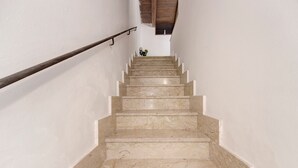 A marble staircase with a handrail, leading to a room with a wooden ceiling.