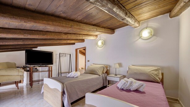 A bedroom with two beds, a TV, a desk, and a chair.