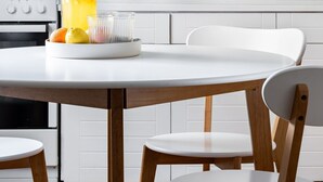 A modern kitchen with white cabinets, a marble backsplash, a stainless steel sink, and a wooden dining table with chairs. - Saronida Coastal Escape 2BR Apartment (Saronikos)