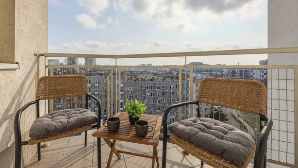 A balcony with wicker chairs, a small table, and a potted plant. - Spacious Apartment with a Balcony | A Place to Work (Warszawa)