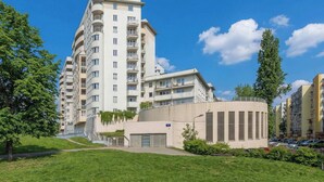 A multi-story residential building with balconies, a parking area, and a grassy courtyard. - Spacious Apartment with a Balcony | A Place to Work (Warszawa)