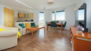 A modern living room with a sofa, coffee table, and dining area. - Spacious Apartment with a Balcony | A Place to Work (Warszawa)