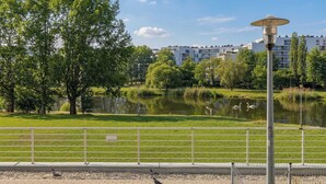 A park with a pond, trees, and a lamp post. - Spacious Apartment with a Balcony | A Place to Work (Warszawa)