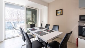 A dining area with a white table, black chairs, and a glass door leading outside. - Comfortable Apartment Amore near Poreč with Balcony for 4 Guests (Kufci)