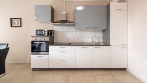 A modern kitchen with white cabinets, a built-in oven, a microwave, and a coffee maker. - Comfortable Apartment Amore near Poreč with Balcony for 4 Guests (Kufci)