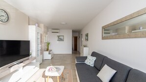 A modern living room with a flat-screen TV, a grey sofa, a small table with a vase, and a hallway leading to another room. - Comfortable Apartment Amore near Poreč with Balcony for 4 Guests (Kufci)
