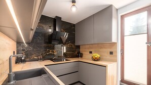 A modern kitchen with a black marble backsplash, a built-in stove, a sink, and a wooden countertop. - Modern Apartment Larisa in Tar with Pool for 4 (Tar)