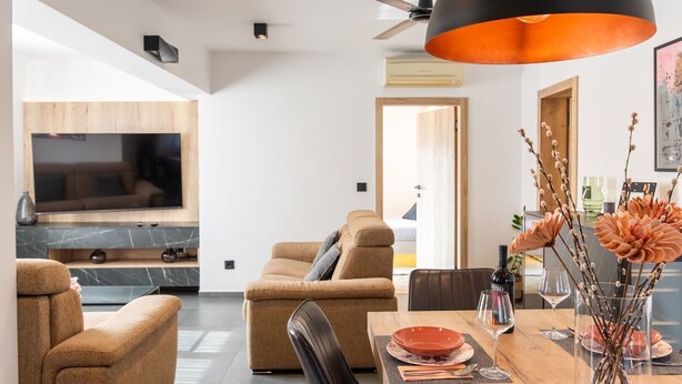 A modern living room with a sofa, a dining table with plates and glasses, and a TV mounted on the wall. - Modern Apartment Larisa in Tar with Pool for 4 (Tar)