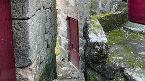 Un bâtiment en pierre avec des portes rouges et un petit escalier menant à un niveau inférieur.