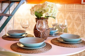 A table set with blue plates, clear wine glasses, and a woven basket containing white flowers. - Casa da Quelha - Douro (Marmelal)