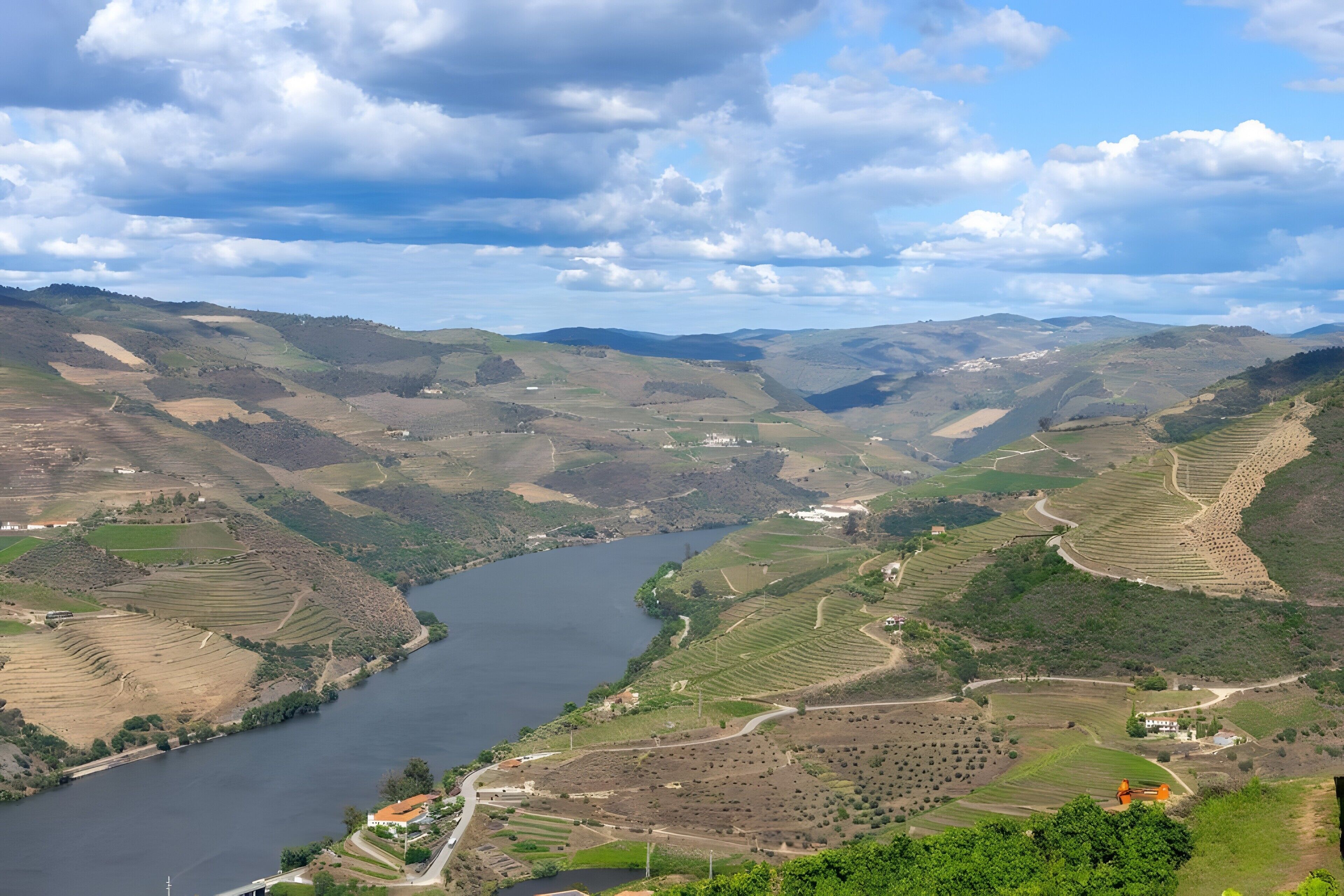 A river valley with terraced fields and a small building near the water.