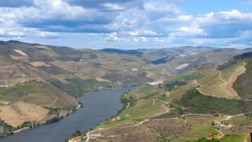 A river valley with terraced fields and a small building near the water.