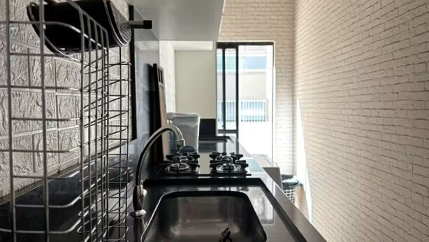 A kitchen with a gas stove, sink, and a metal rack. - Spacious apartment 160m from the beach, 3 bedrooms, barbecue. (Itapema)