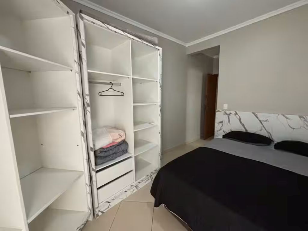 A bedroom with a bed, a wardrobe, and a door leading to another room.