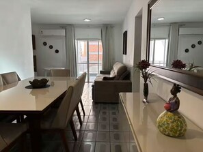 Ein modernes Wohnzimmer mit Essbereich, einer Couch, einem Couchtisch und einer dekorativen Vase.
