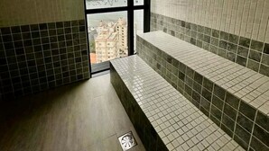 A bathroom with a tiled floor, a window with a view, and a bench. - Apartment with Sea View • Comfort and Leisure in Itapema (Itapema)