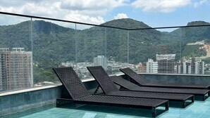 A rooftop pool with lounge chairs and a cityscape view. - Apartment with Sea View • Comfort and Leisure in Itapema (Itapema)