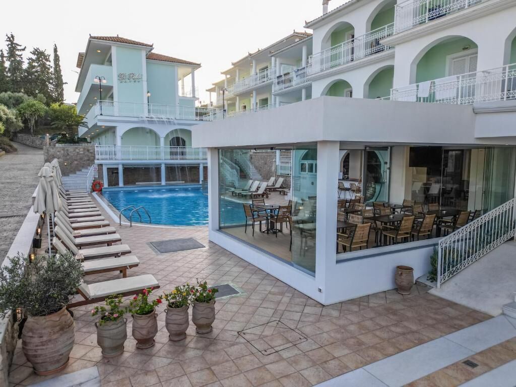 Zona junto a la piscina con sillas de descanso, comedor y una escalera que sube a plantas superiores.