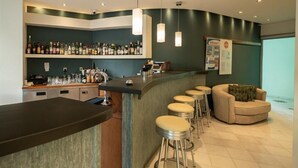 Zona de bar con mostrador, taburetes y un área de estar con sofá.
