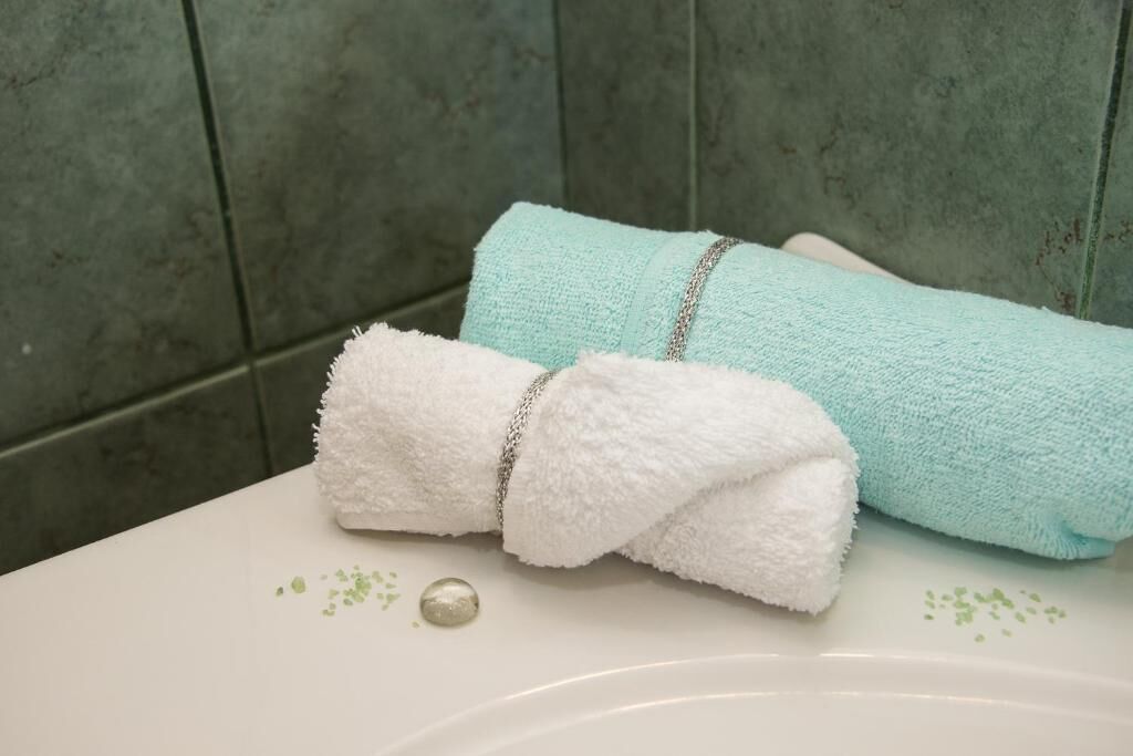 A bathroom with a white sink, a blue towel, and a white towel.