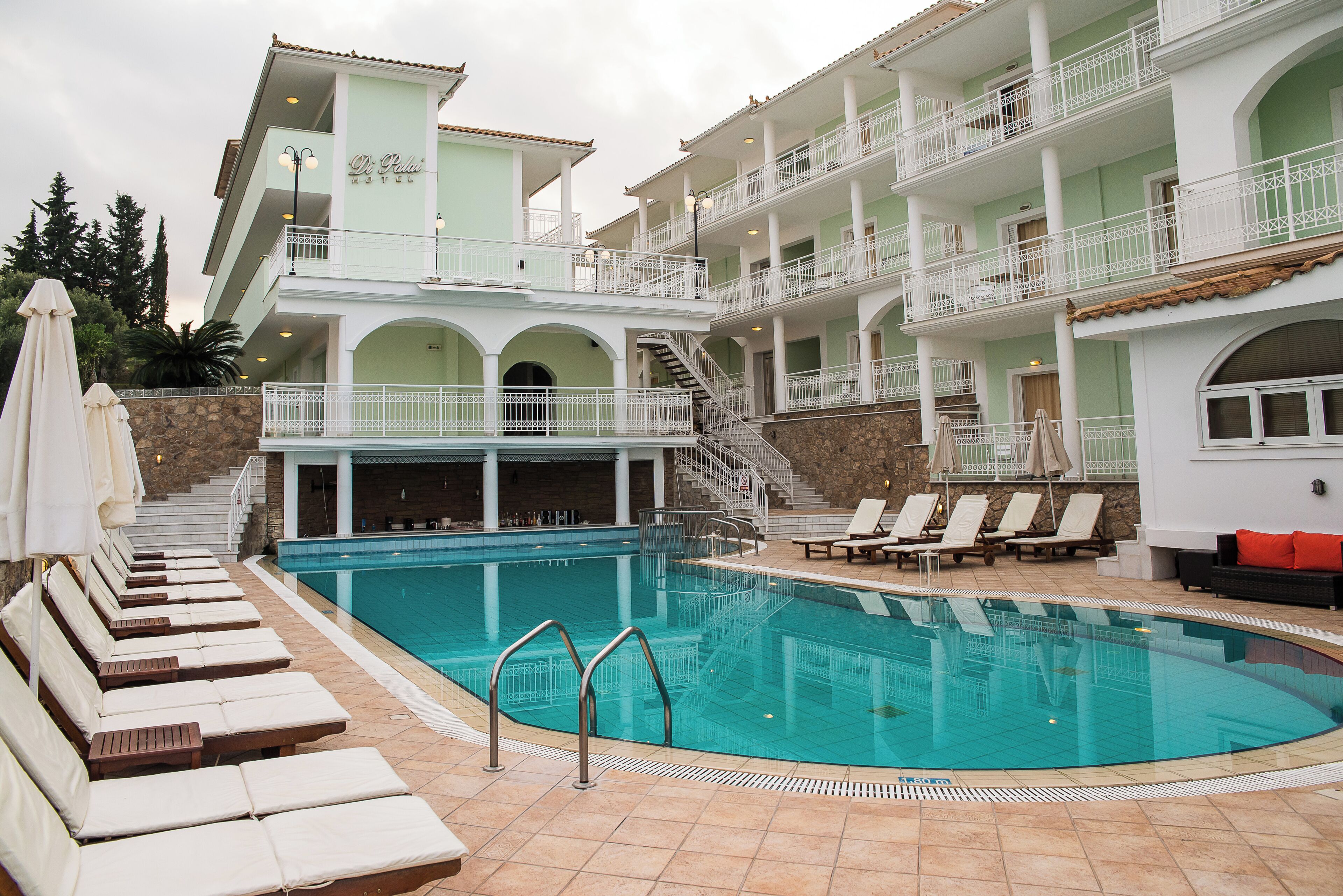 A hotel with a swimming pool, lounge chairs, and a bar area.