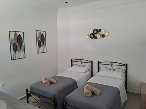 Ein Zimmer mit zwei Einzelbetten, jeweils mit einem zusammengerollten Handtuch darauf. An der Wand hängen zwei gerahmte Blätterbilder.