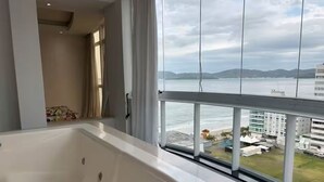 Un baño con bañera y vistas al mar a través de amplios ventanales.