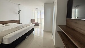Habitación de hotel moderna con cama, televisor de pantalla plana, banco de madera y vistas al exterior.