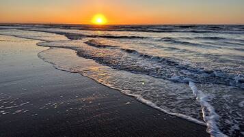 A beach with waves and a sunset.