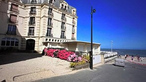 Ein Gebäude mit mehreren Balkonen, blauem Himmel und Meerblick.