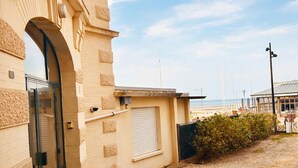Ein Gebäude mit einem großen Bogenportal, einem kleinen überdachten Bereich und Blick auf den Strand.