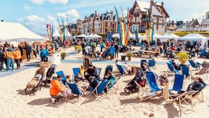 Eine Veranstaltung am Strand mit Zelten, Flaggen und Menschen.