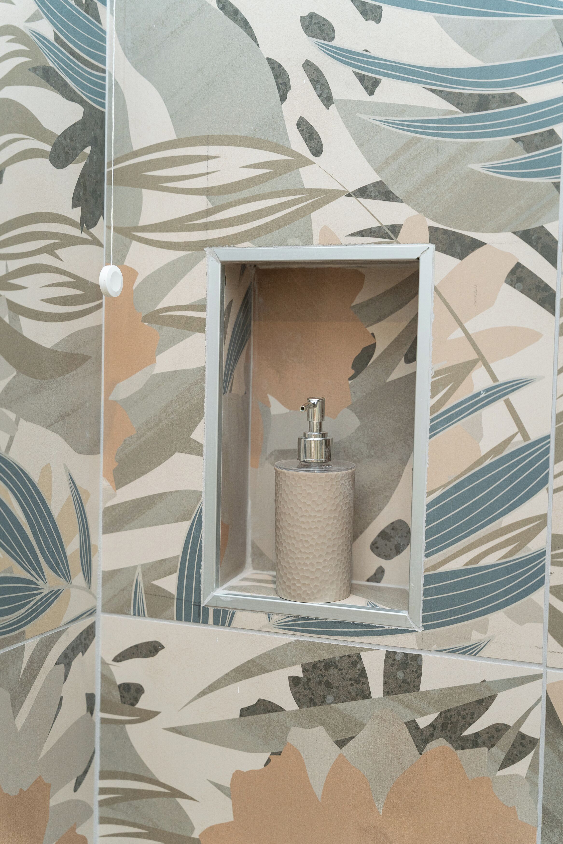 A bathroom with a textured wall, a mirror, and a soap dispenser.