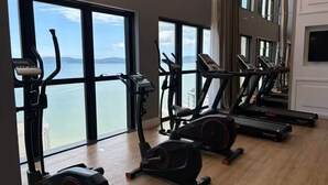 Een fitnessruimte met cardioapparatuur en uitzicht op zee.
