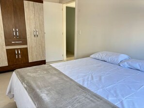 Ein Schlafzimmer mit einem Bett, einem Kleiderschrank und einer Tür zu einem anderen Raum.