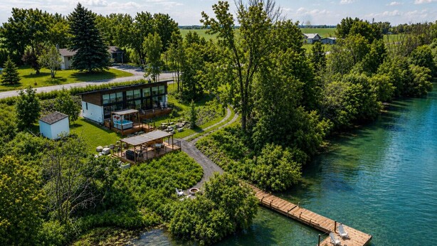 Une propriété au bord du lac, comprenant une maison moderne, un quai et un espace verdoyant.