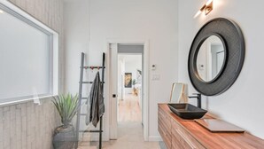 Une salle de bain moderne avec un meuble-lavabo en bois, un miroir rond et un porte-serviettes.