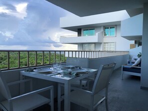 Ein Balkon mit Esstisch, gedeckt für zwei Personen, mit Blick auf eine üppige grüne Landschaft.